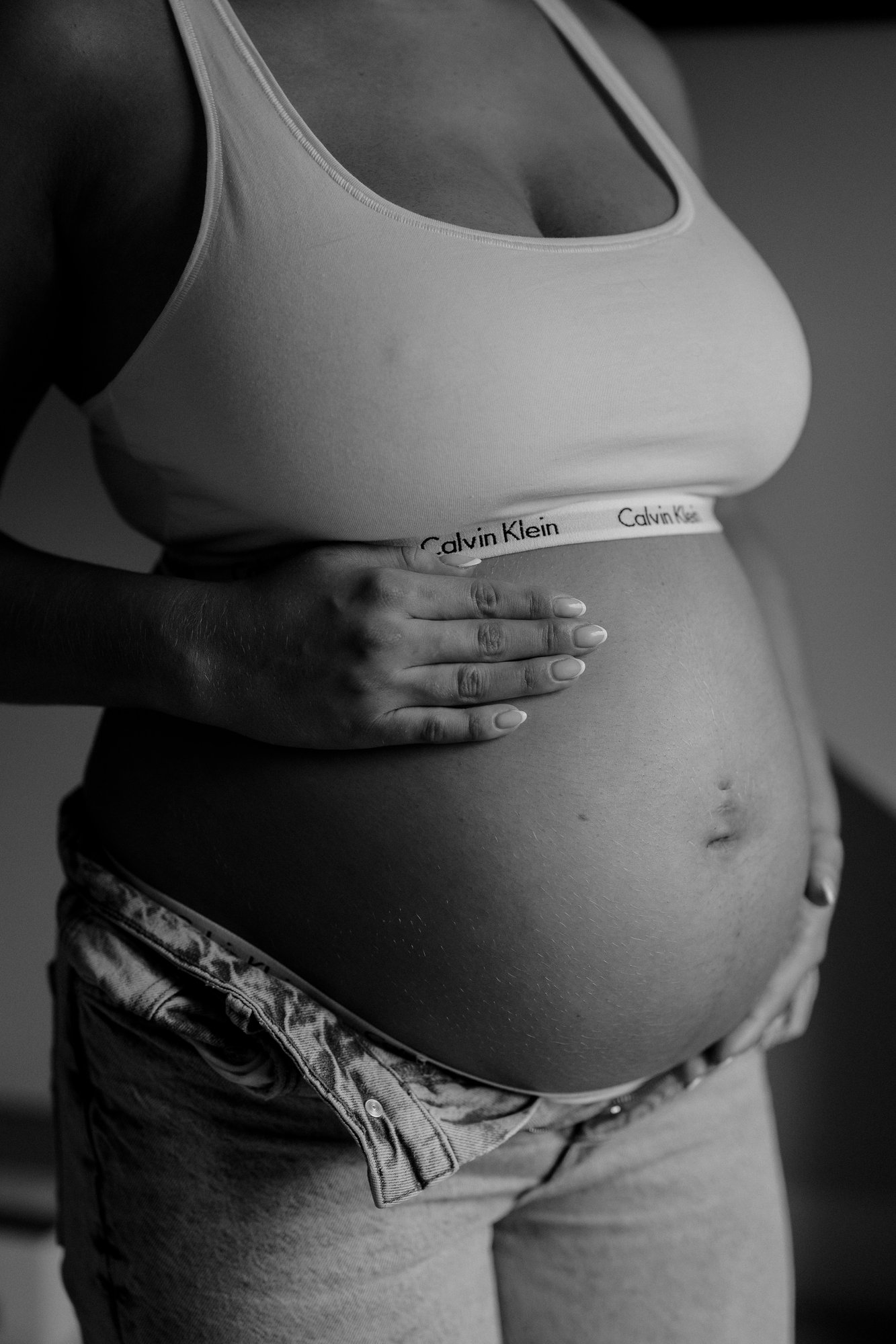 Intimate black and white close-up of an expectant mother's bump, hand resting gently