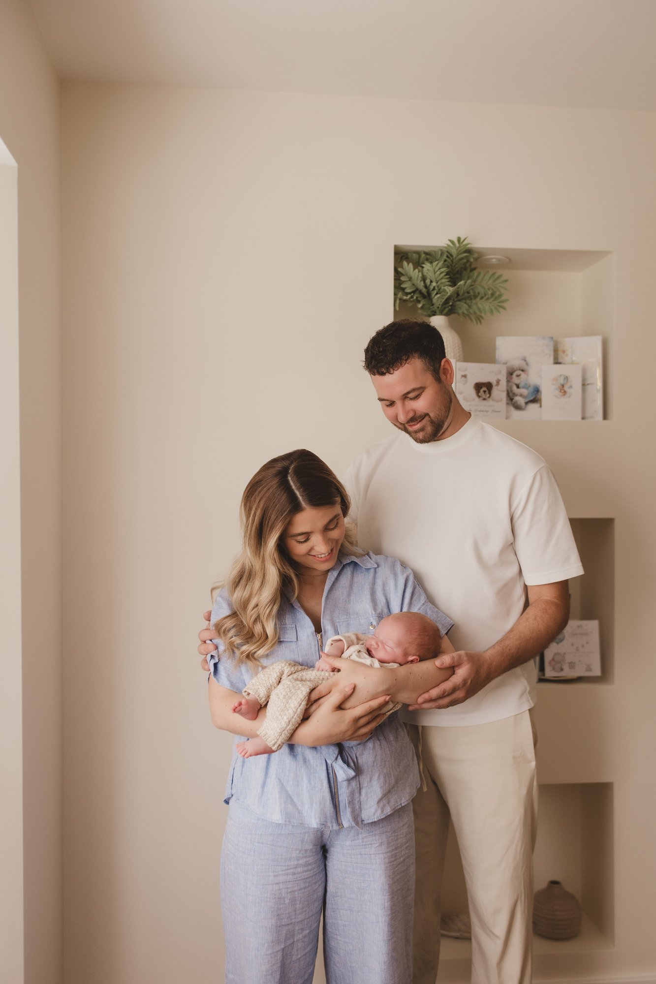 New parents standing together in the nursery holding their newborn baby