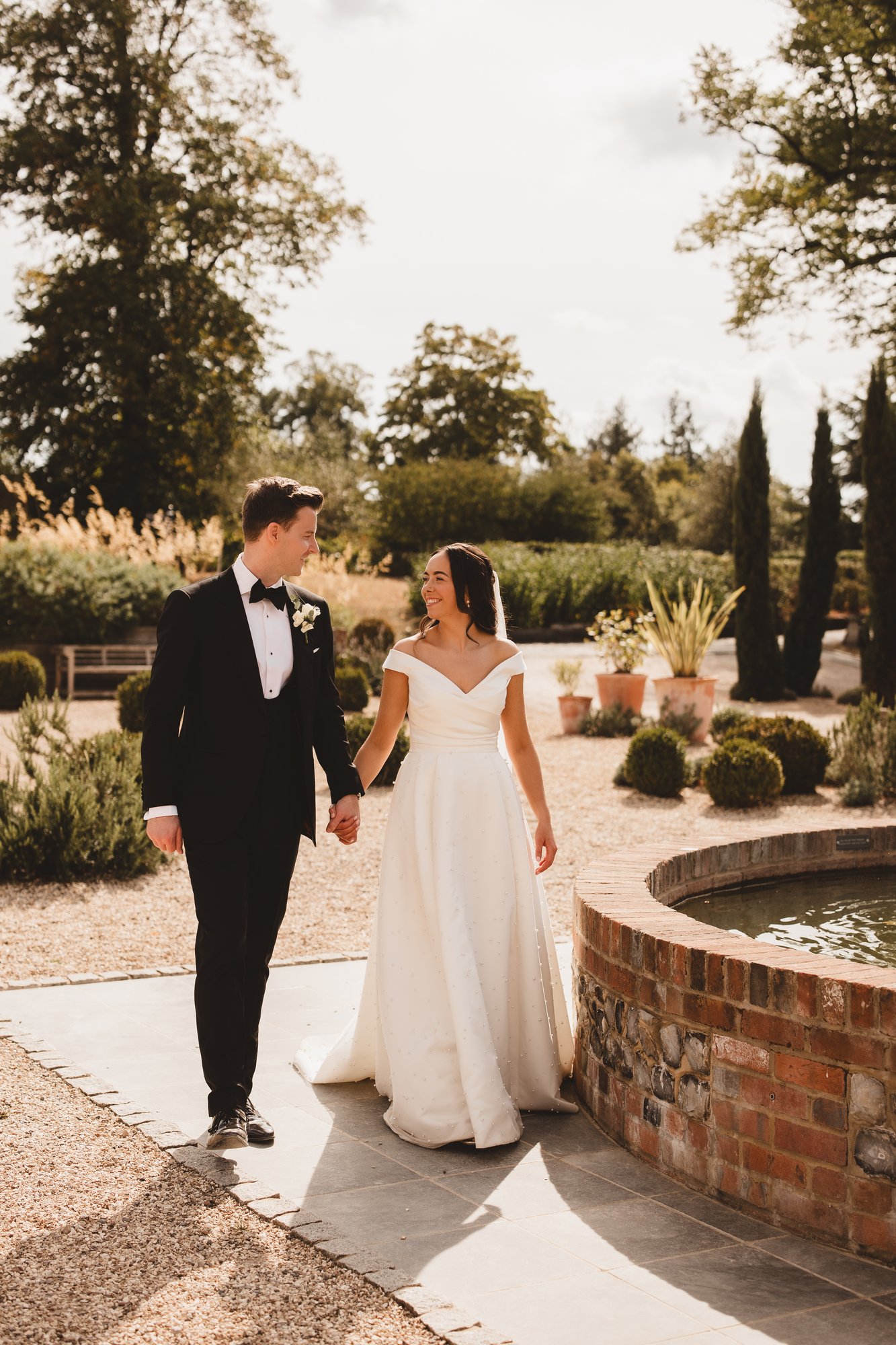 Bride and groom walking through formal English gardens