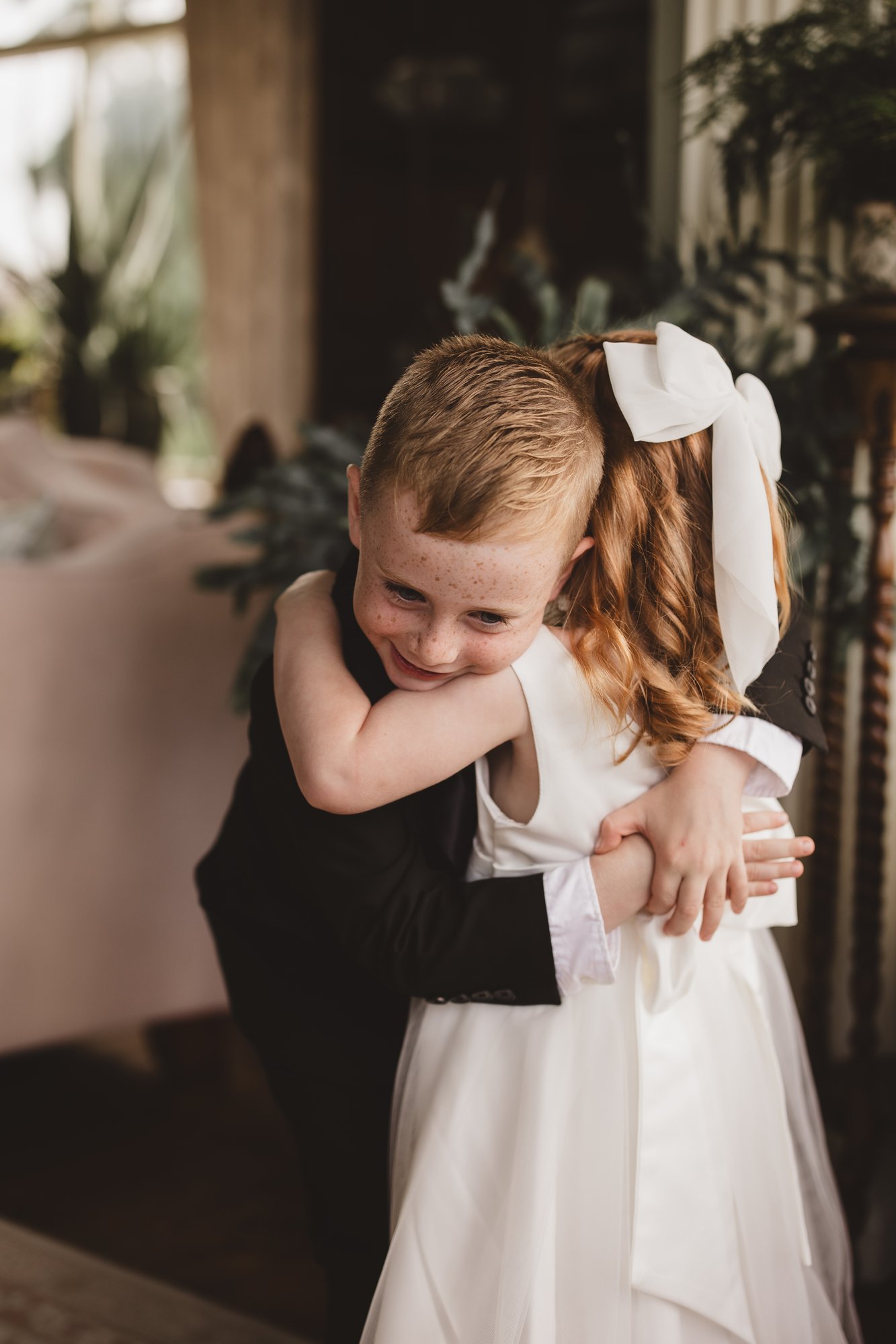 Page boy and flower girl sharing a hug at a wedding